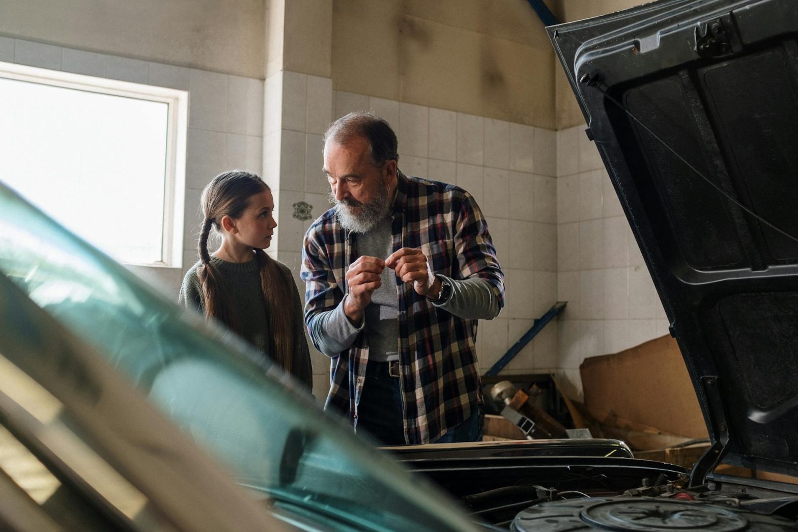 Father and daughter bonding over car repair in a garage workshop.