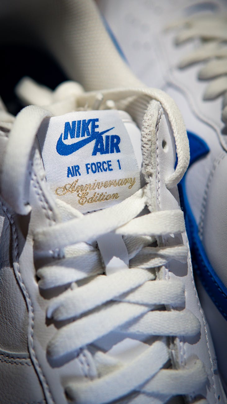 White Nike sneakers featuring blue accents and anniversary edition label.