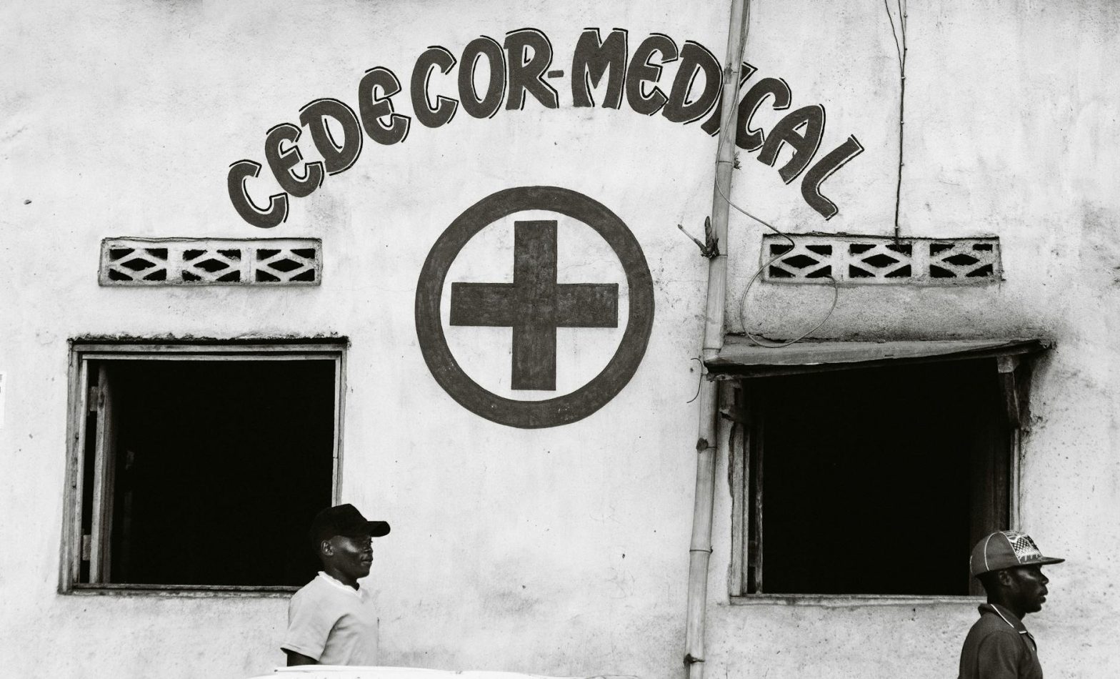Black and white image of CEDECOR Medical with two men walking past the building's exterior.
