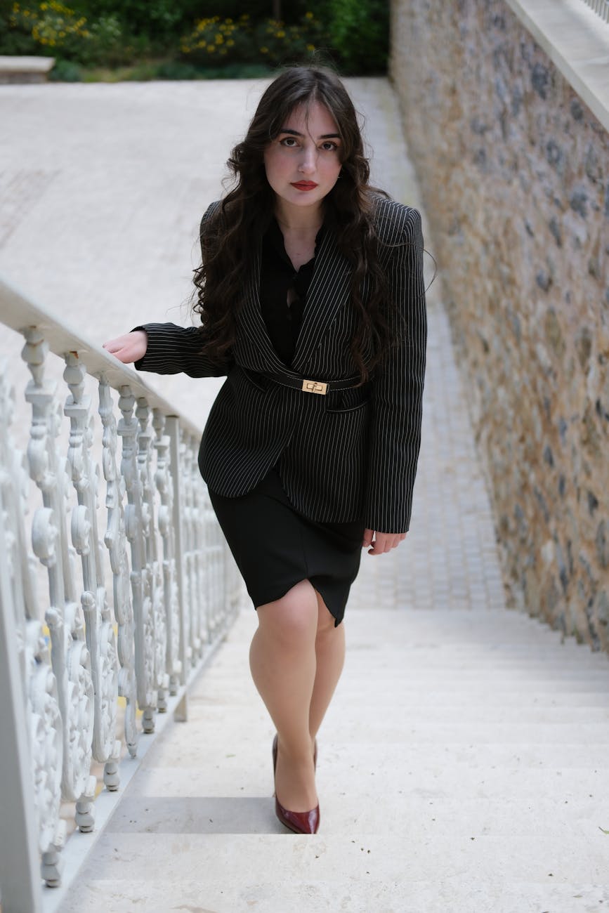 Confident businesswoman in a pinstripe suit jacket walking up outdoor stairs.