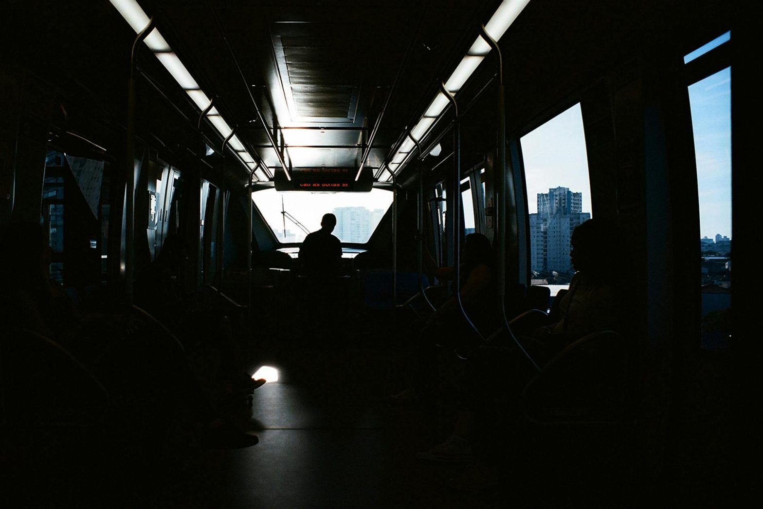 Atmospheric silhouette of commuters inside a train during daytime travel, highlighting urban transit.