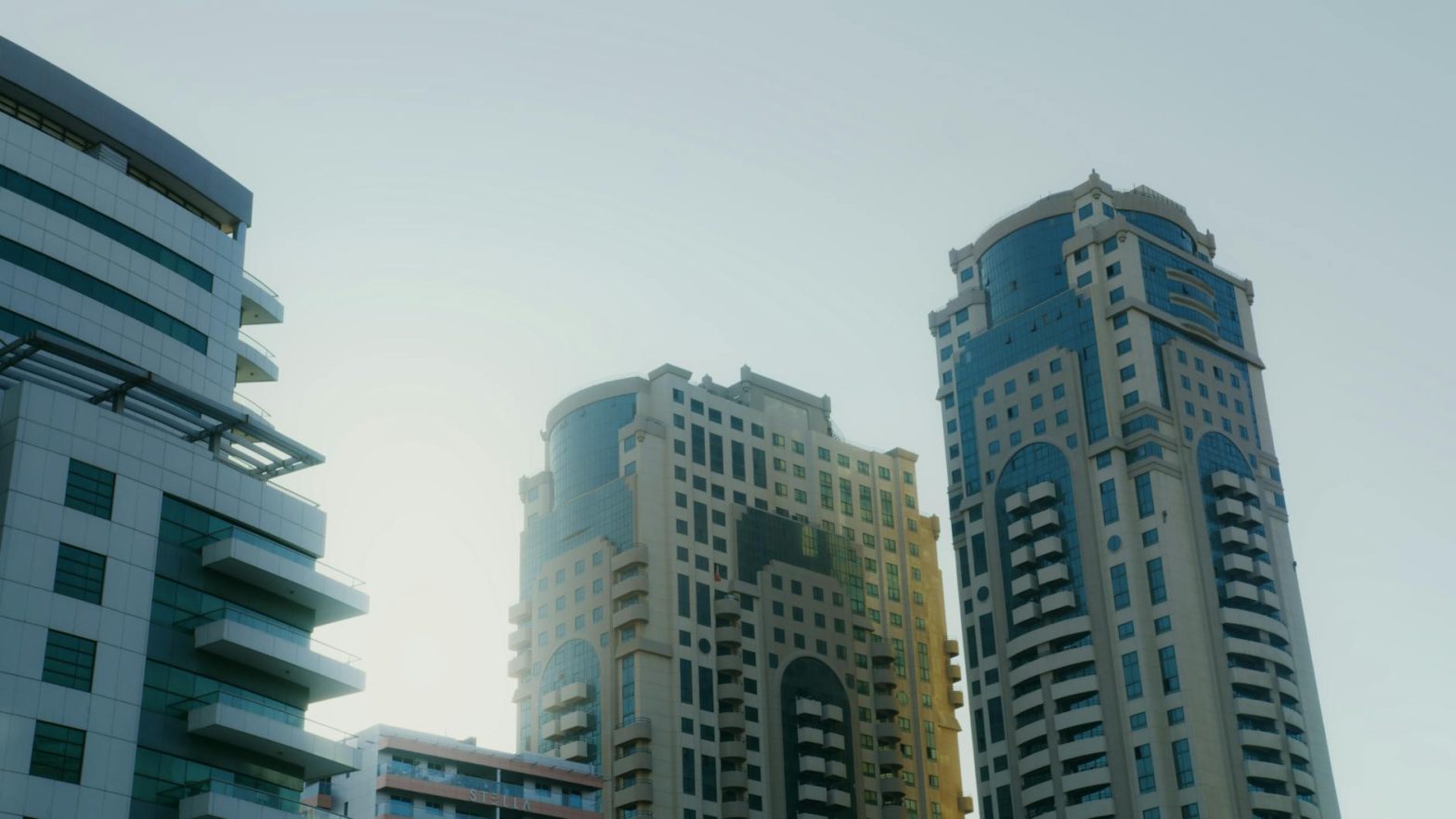 Low angle view of modern high-rise buildings under clear sky in Dubai, showcasing architectural elegance.