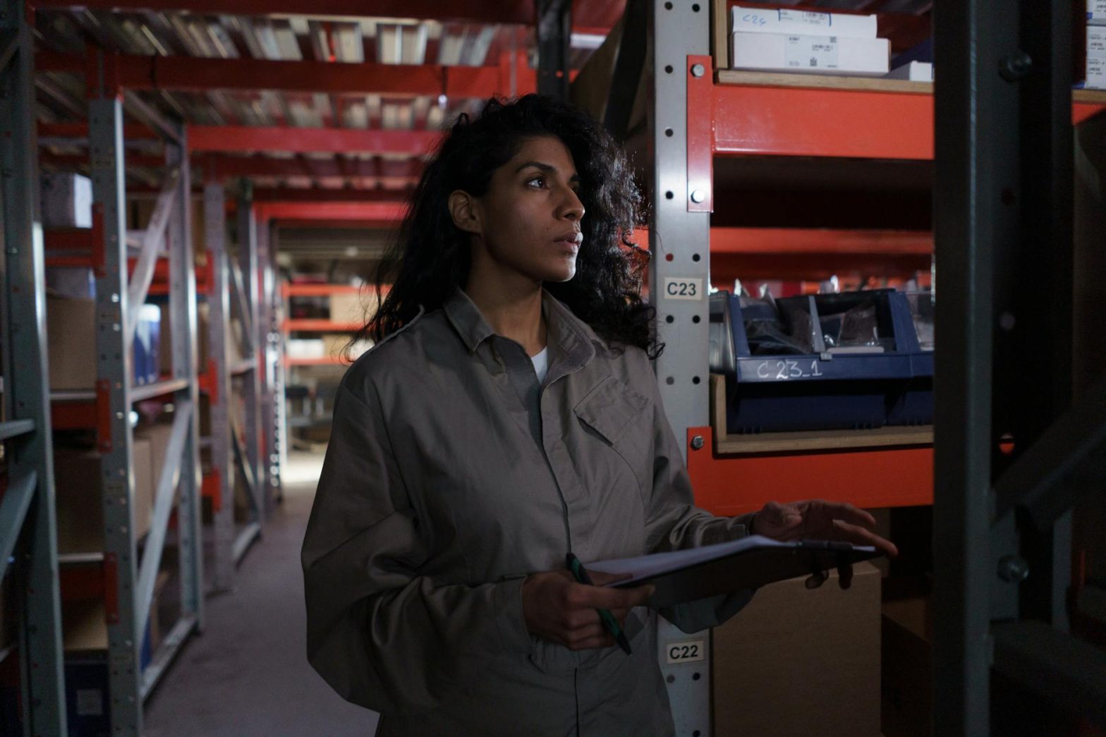 Female warehouse worker checking inventory in an industrial storage facility.