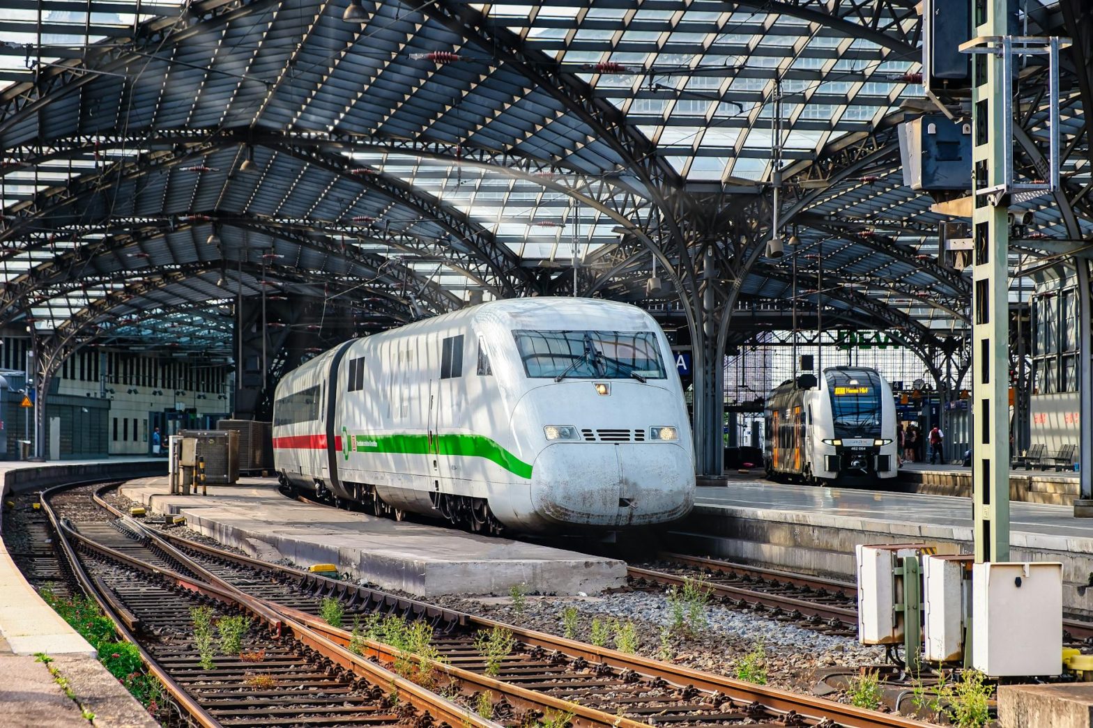 High-speed trains at a busy European train station under an architectural roof.